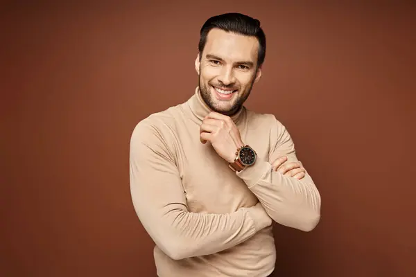 Happy man with bristle posing in turtleneck and touching his chin on beige background, male model — Stock Photo
