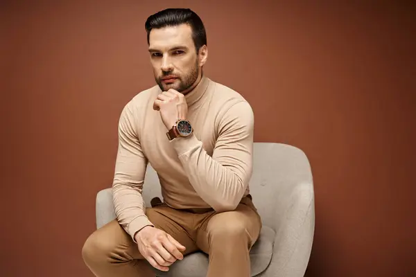 Handsome and serious man with bristle sitting on comfortable armchair on beige background — Stock Photo