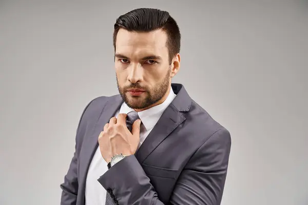 Intense gaze from a handsome businessman with bristle posing in a sharp suit on grey background — Stock Photo