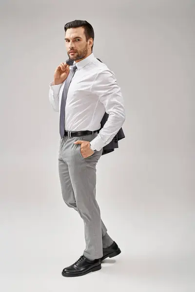 Hombre de negocios de 30 años con chaqueta de cerdas sobre el hombro mientras está de pie con la mano en el bolsillo - foto de stock