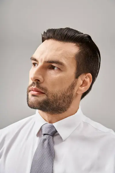 Retrato de hombre de negocios guapo en camisa blanca y corbata posando con confianza sobre fondo gris - foto de stock