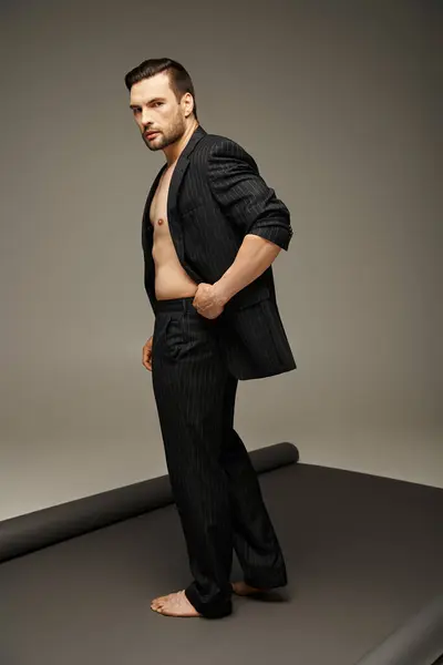 Modischer und gutaussehender Mann mit nackter Brust und Nadelstreifenanzug posiert auf grauem Hintergrund — Stockfoto