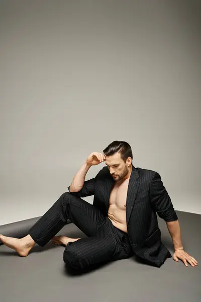 Homem elegante e bonito com peito nu posando em terno pinstripe no fundo cinza, moda — Fotografia de Stock
