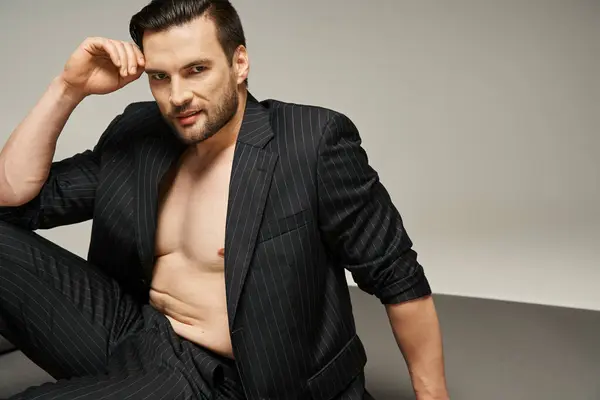 Fröhlicher und gutaussehender Mann mit nackter Brust posiert im Nadelstreifenanzug auf grauem Hintergrund, Mode — Stockfoto