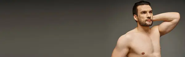 Портрет мускулистого и без рубашки мужчины с обнаженной грудью и щетиной, позирующей на сером фоне, баннер — стоковое фото
