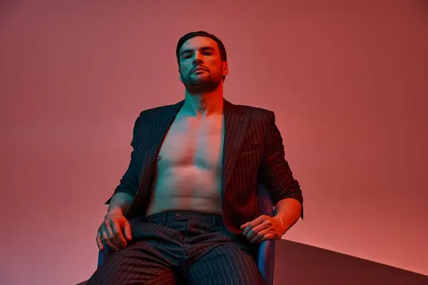 Bel homme avec poitrine nue et poil posant en costume de tapisserie en studio avec lumière rouge et bleue — Photo de stock