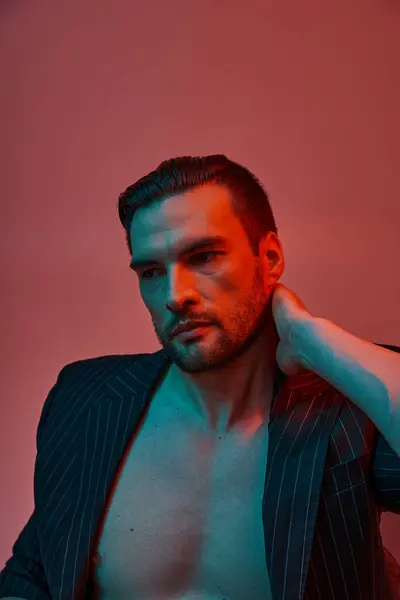 Portrait of man with bare chest posing in elegant pinstripe suit in studio with red and blue light — Stock Photo