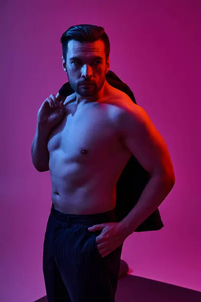 Seducente uomo senza camicia con petto nudo e giacca tenuta setole mentre posa su sfondo viola — Foto stock