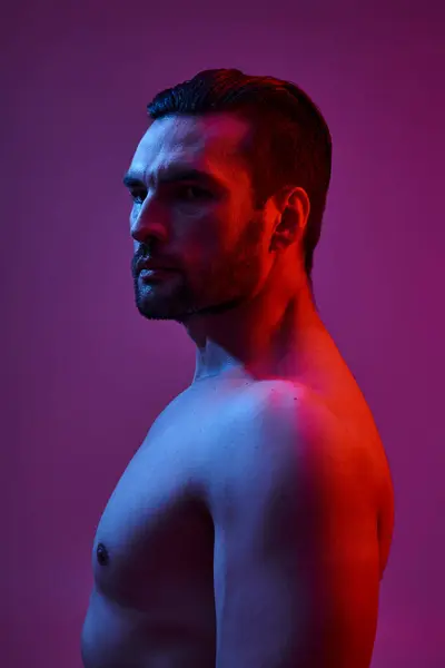 Retrato de hombre seductor y musculoso con cerdas posando sobre fondo púrpura, tiro de moda - foto de stock