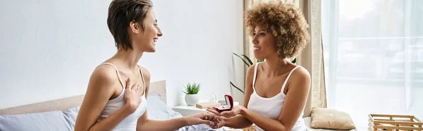 Happy african american woman holding engagement ring and doing proposal to girlfriend, banner — Stock Photo