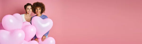 San Valentino banner, sognante interrazziale coppia lesbica sorridente vicino palloncini a forma di cuore — Foto stock