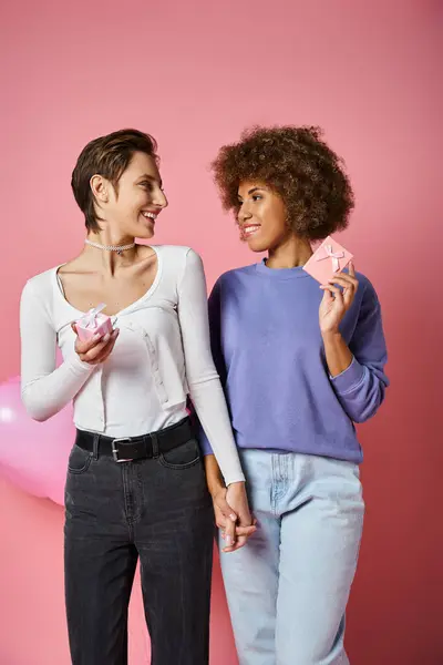 Happy multicultural lesbian couple holding gift boxes standing together on Valentines day — Stock Photo