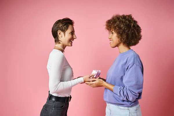 Cheerful lesbian woman giving present to happy african american girlfriend on Valentins day — Stock Photo