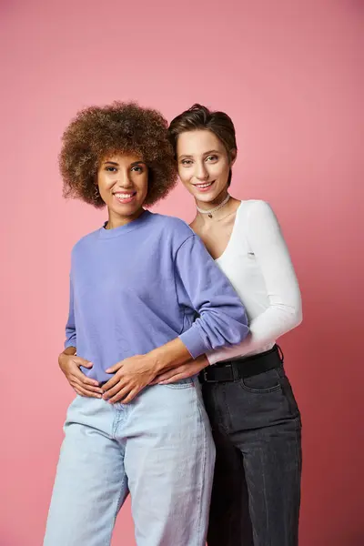Sorrindo mulher lésbica abraçando a namorada afro-americana em roupas casuais no fundo rosa — Fotografia de Stock