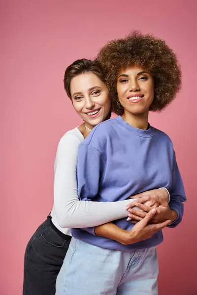 Happy woman hugging her african american girlfriend on pink background, lgbtq couple love — Stock Photo
