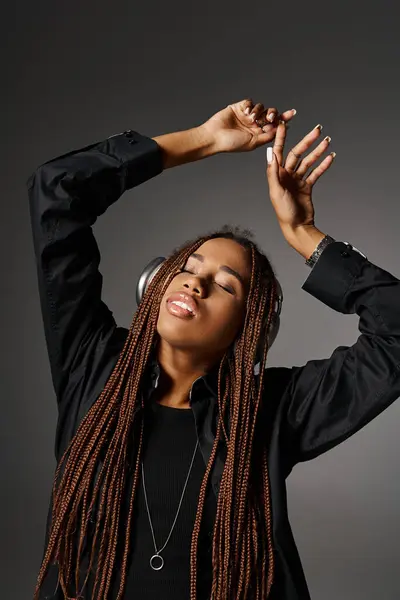 Extático jovem afro-americano menina em 20s com dreadlocks ouvir música no fundo cinza — Fotografia de Stock