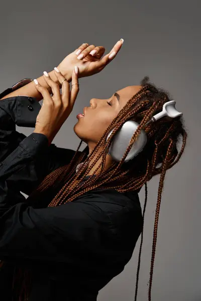 African american woman with closed eyes and dreadlocks listening music in headphones on grey — Stock Photo