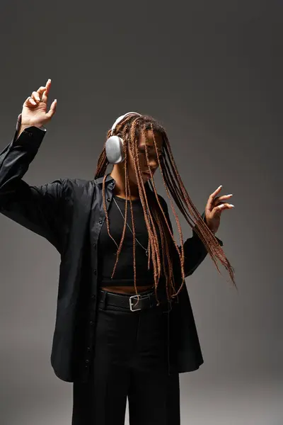 Joven afroamericana mujer en 20s bailando mientras escucha música en auriculares inalámbricos, movimiento - foto de stock