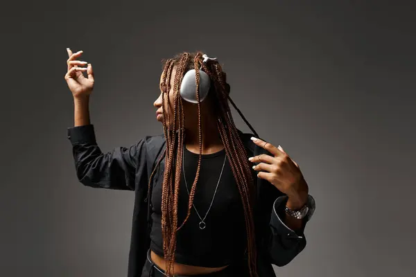 Ecstatic dance of african american woman in 20s with dreadlocks and wireless headphones on grey — Stock Photo