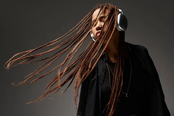 Ecstatic dance of carefree african american girl with dreadlocks and wireless headphones on grey — Stock Photo