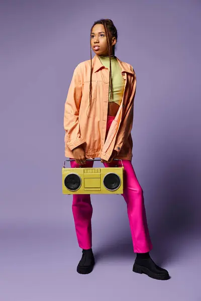 Dreamy african american girl with dreadlocks standing with retro boombox on purple backdrop — Stock Photo