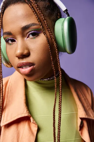 Sereno africano americano ragazza in 20s ascolto musica in cuffie wireless su sfondo viola — Foto stock