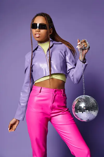 African american model in futuristic sunglasses and headphones standing with disco ball on purple — Stock Photo