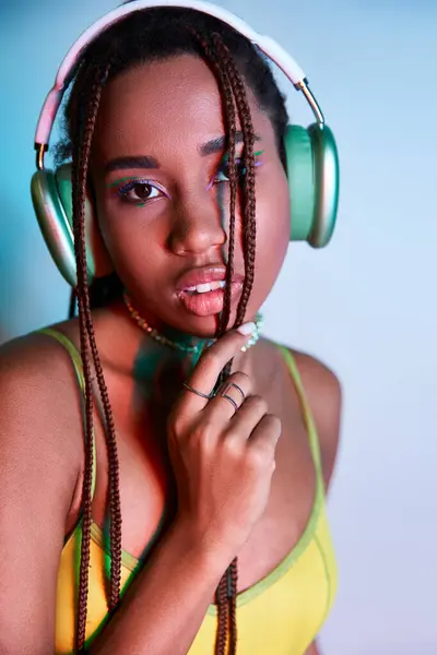 Alluring african american woman with dreadlocks in wireless headphones looking at camera on blue — Stock Photo