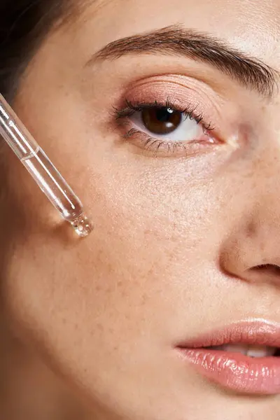 Um close-up de uma jovem mulher branca com pele limpa aplicando soro com pipeta cosmética — Fotografia de Stock