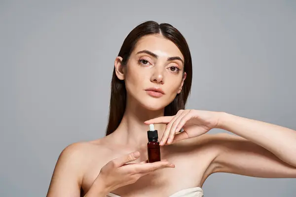 Uma jovem caucasiana com cabelo morena segurando uma garrafa de produto de cuidados com a pele, mostrando uma tez radiante e saudável. — Fotografia de Stock