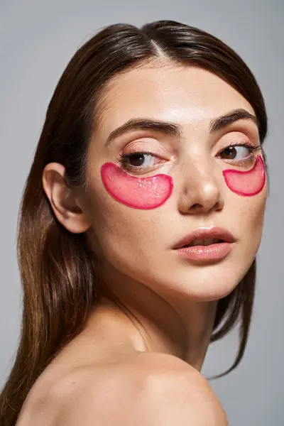 Eine junge kaukasische Frau mit rosa Augenklappen, die ihr Gesicht in einem Studio akzentuieren. — Stockfoto