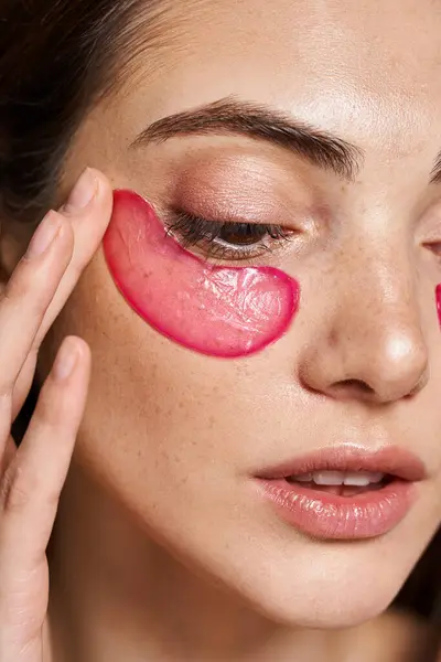 Uma jovem mulher caucasiana com pele limpa e remendo de olhos rosa em seu rosto em um ambiente de estúdio. — Fotografia de Stock