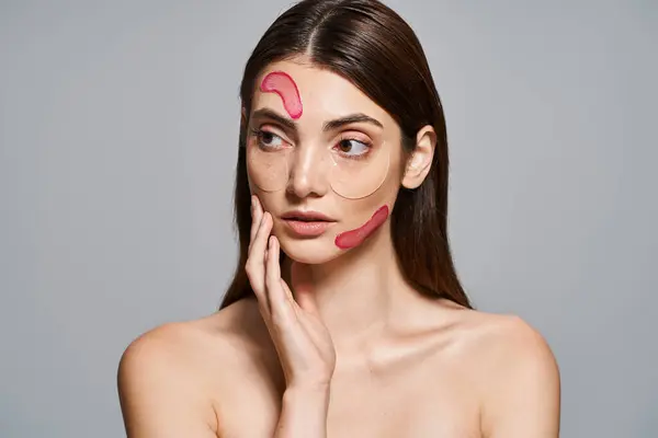 Uma jovem caucasiana com cabelo morena usa um rosto rosa remendos hidratantes, promovendo autocuidado e relaxamento. — Fotografia de Stock