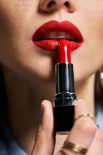 Young woman holds a vibrant red lipstick in her hand, radiating confidence and beauty. — Stock Photo