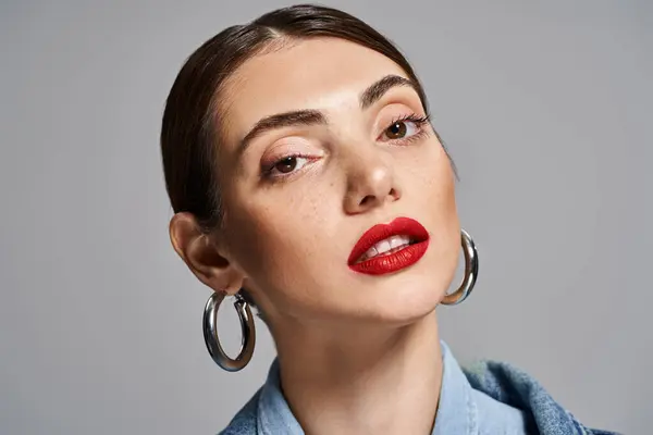 A young Caucasian woman with brunette hair and clean skin wearing large hoop earrings and bold red lipstick. — Stock Photo