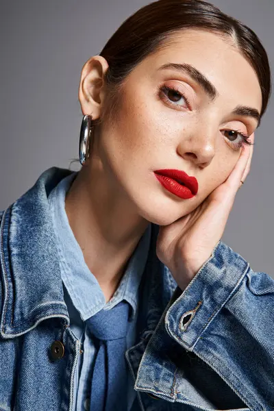 Une jeune femme caucasienne avec des cheveux bruns dans une veste en denim et rouge à lèvres rouge vif respire la confiance et le style. — Photo de stock