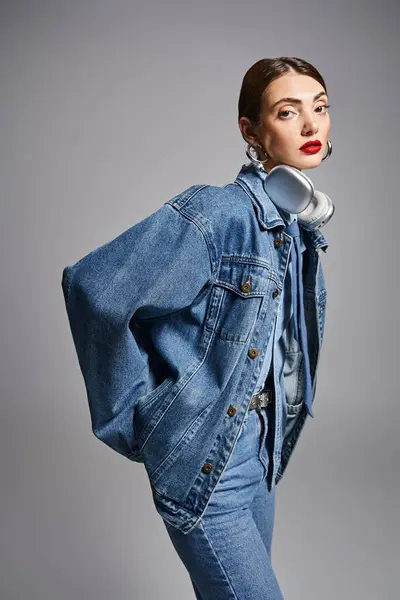 A stylish young Caucasian woman with brunette hair wearing a denim jacket and jeans, exuding confidence and attitude. — Stock Photo