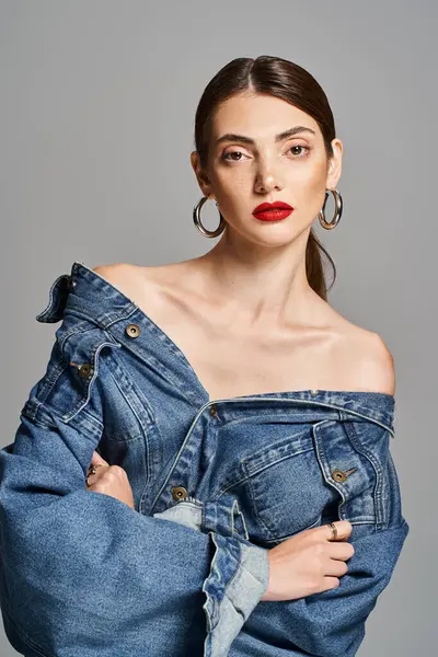A young Caucasian woman with brunette hair wearing a trendy jean jacket and bold red lipstick. — Stock Photo