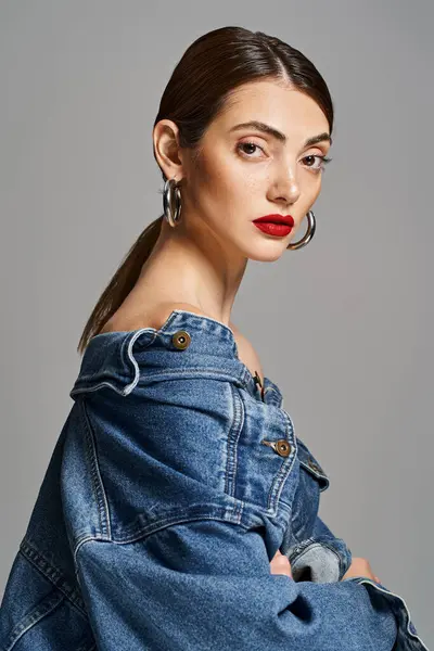 A young Caucasian woman with brunette hair and clean skin, wearing a jean jacket and bold red lipstick. — Stock Photo
