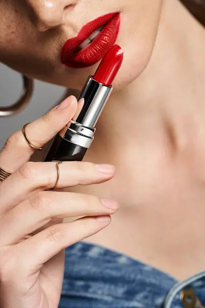A young cropped woman holds a vibrant red lipstick in her hand, showcasing bold and confident beauty. — Stock Photo