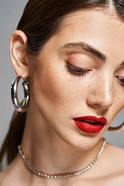 A young caucasian woman with brunette hair wearing red lipstick and hoop earrings. — Stock Photo
