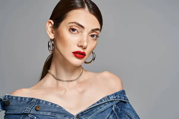 A stylish young woman with brunette hair wearing a denim dress and bright red lipstick. — Stock Photo