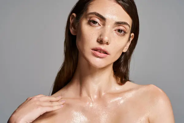 Uma jovem mulher caucasiana com cabelo morena e pele limpa posa para a câmera com um corpo molhado brilhante. — Fotografia de Stock