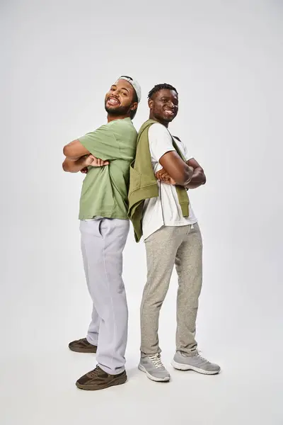 Juneteenth, longitud completa de amigos afroamericanos de pie con los brazos cruzados sobre fondo gris - foto de stock