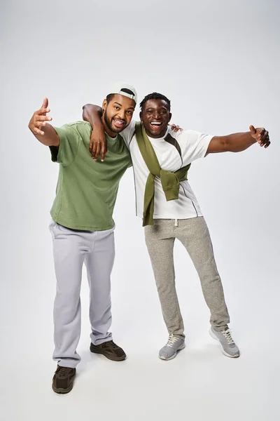 Счастливые июньские, позитивные и молодые африканские американские друзья обнимаются на сером фоне — Stock Photo