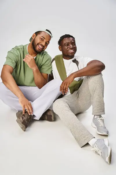 Happy Juneteenth celebration, young african american man sitting with friend on grey background — Stock Photo