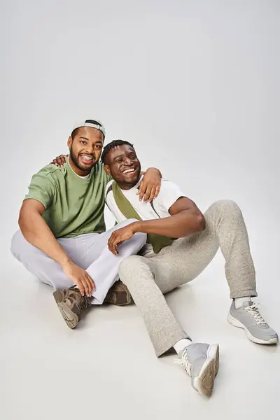 Juneteenth celebração, animado e jovem afro-americano amigos do sexo masculino abraçando em fundo cinza — Fotografia de Stock