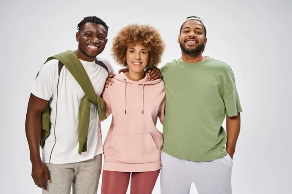 Cheerful african american friends standing and hugging on grey background, Juneteenth celebration — Stock Photo