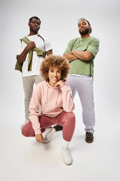 Happy african american woman smiling near male friends posing on grey background, solidarity — Stock Photo