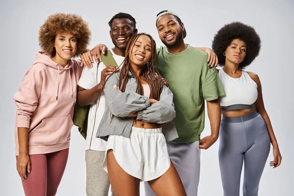 Happy african american woman posing near friends in sportswear on grey backdrop, Juneteenth — Stock Photo